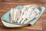 Collection of birch wood utensils on palm leaf dish