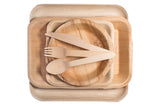 Birch wood fork, knife, and spoon on palm leaf dishes